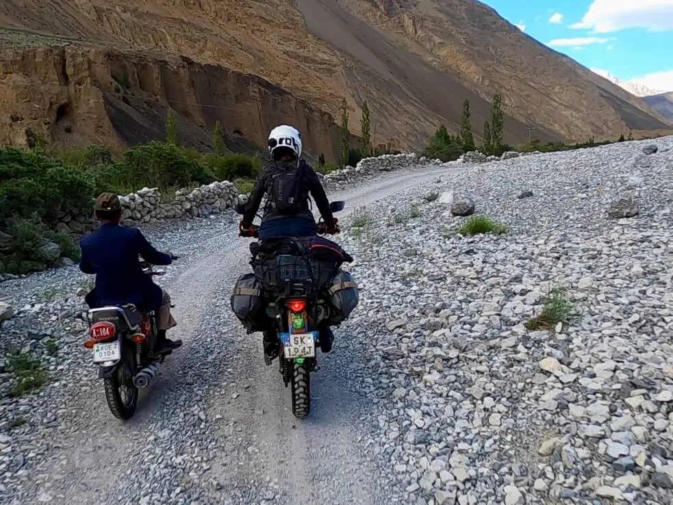 Local and western motorcycle on the rocky section of the road to Shimshal